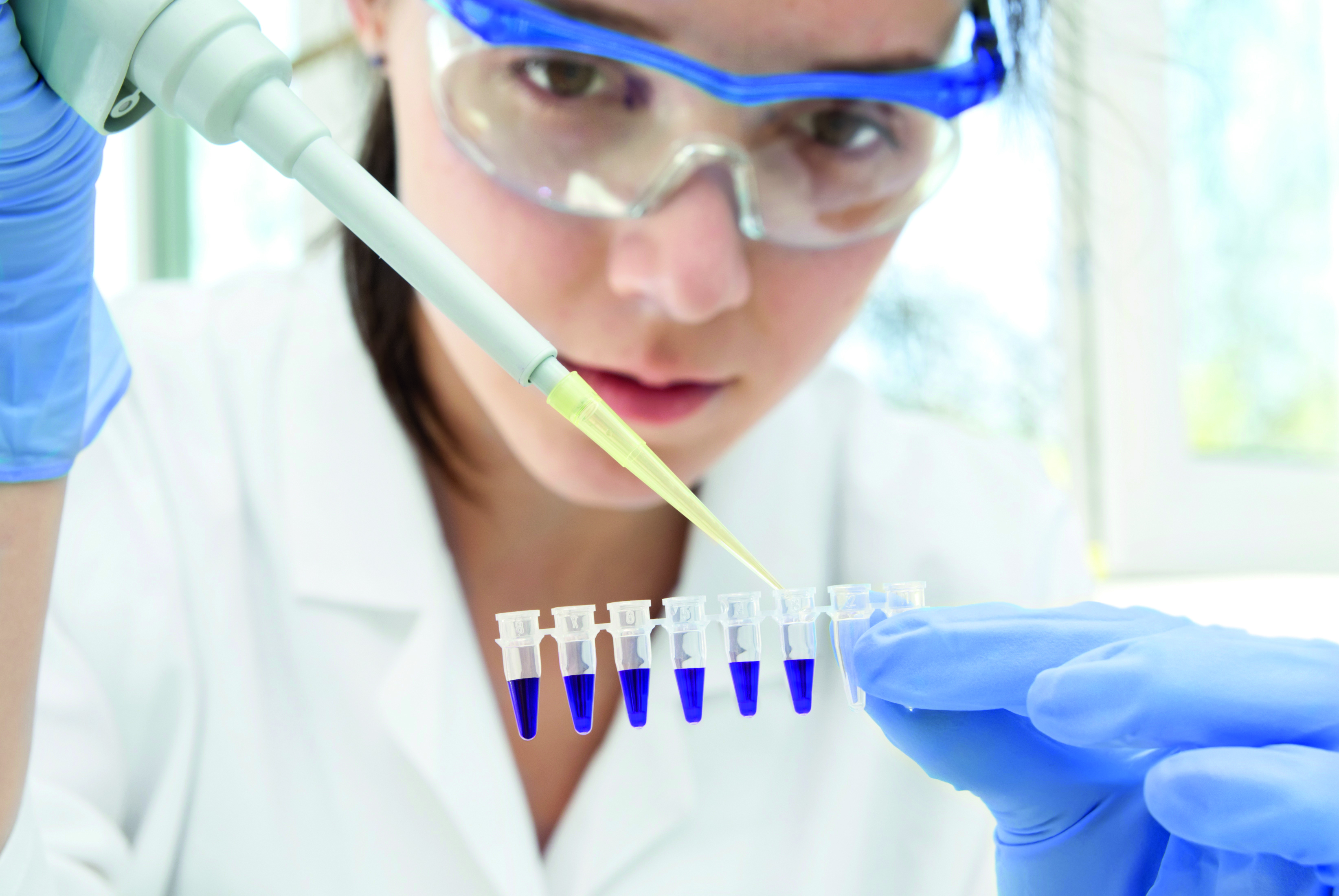 The photo shows a woman pipetting liquds. Photo stands for the analytical services provided by the presented company.