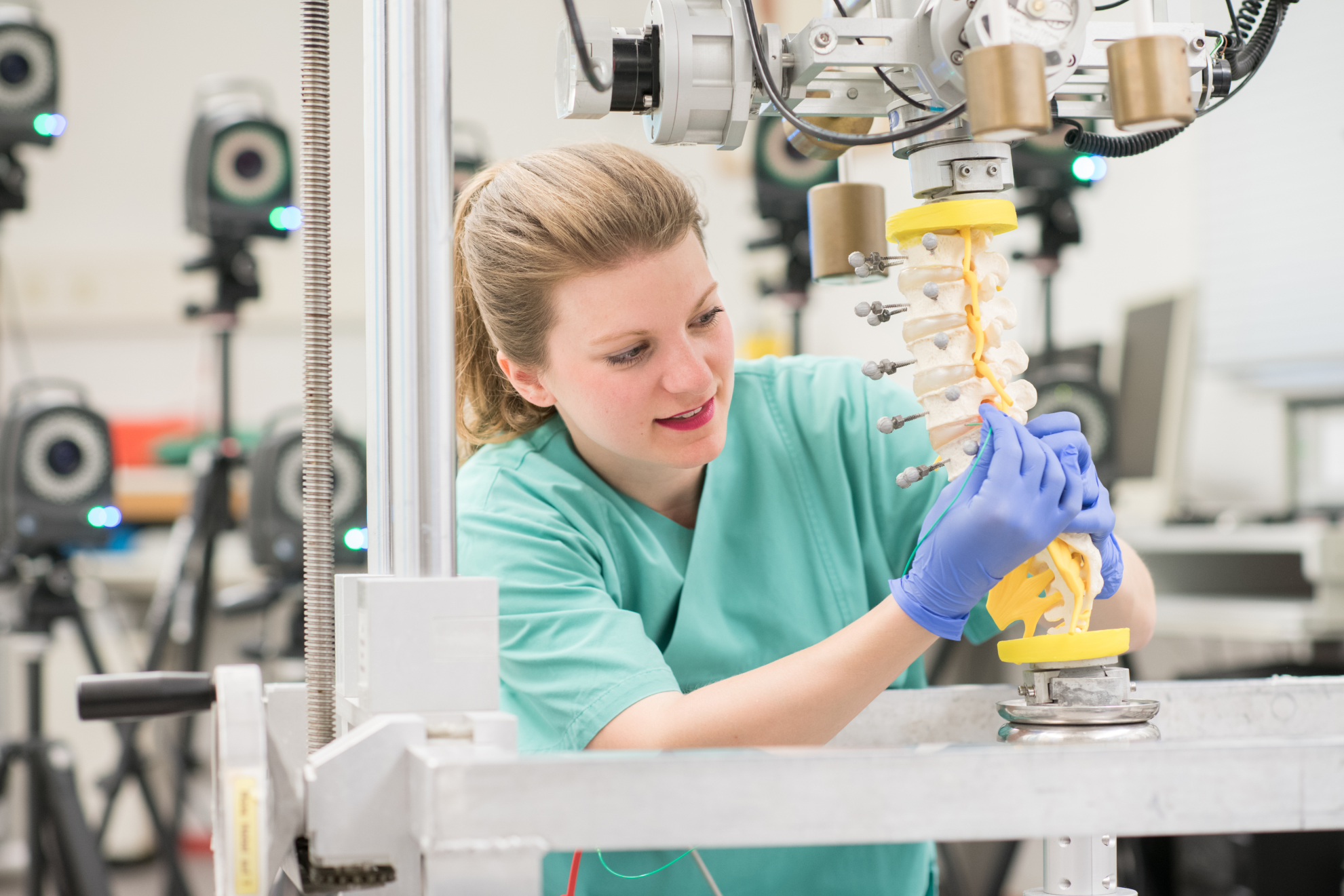 Doctoral student Laura Zengerle uses a plastic model to demonstrate how the spinal stress simulator works.