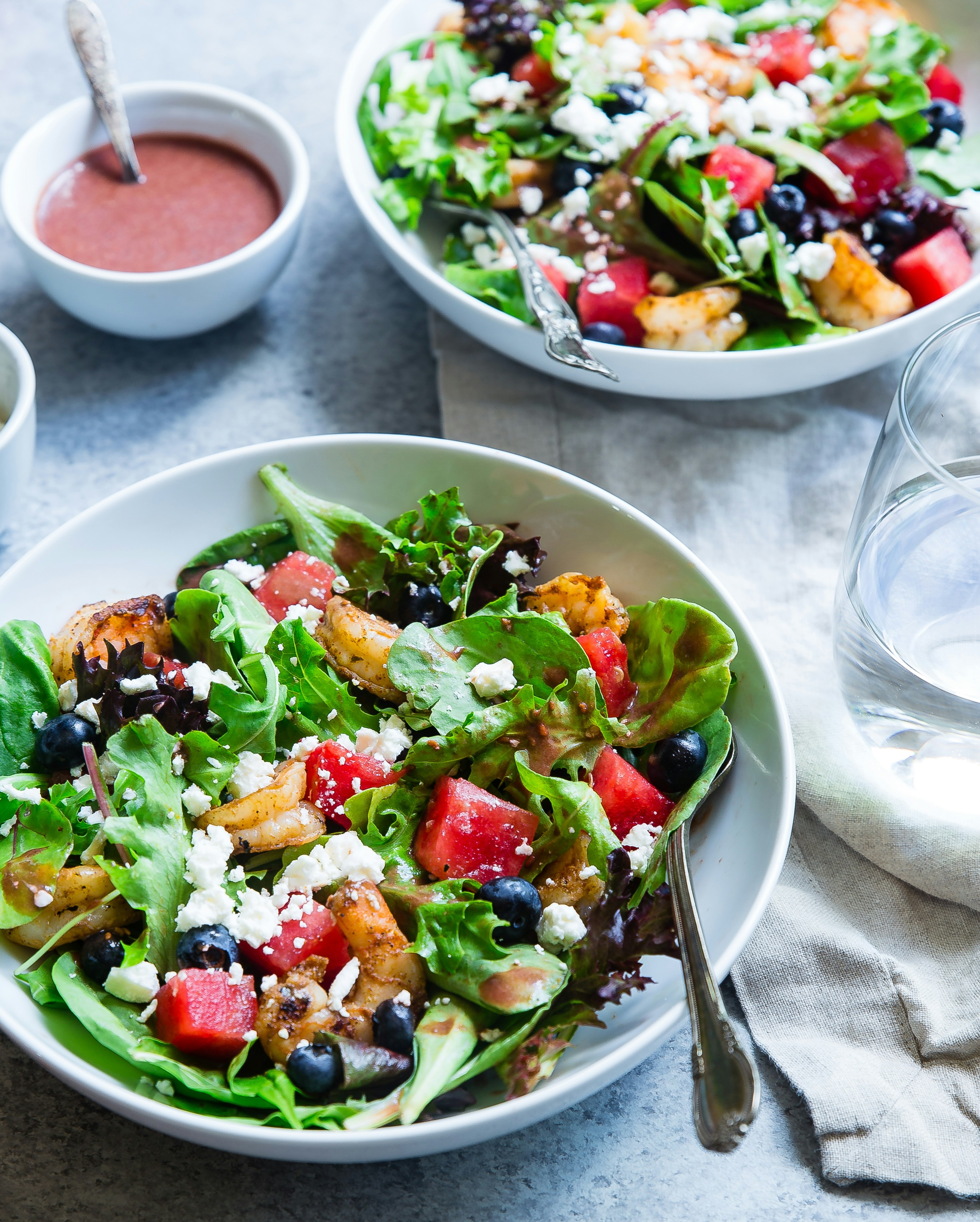 Eine Schüssel bunter Salat und Gemüse mit einem Glas Wasser.