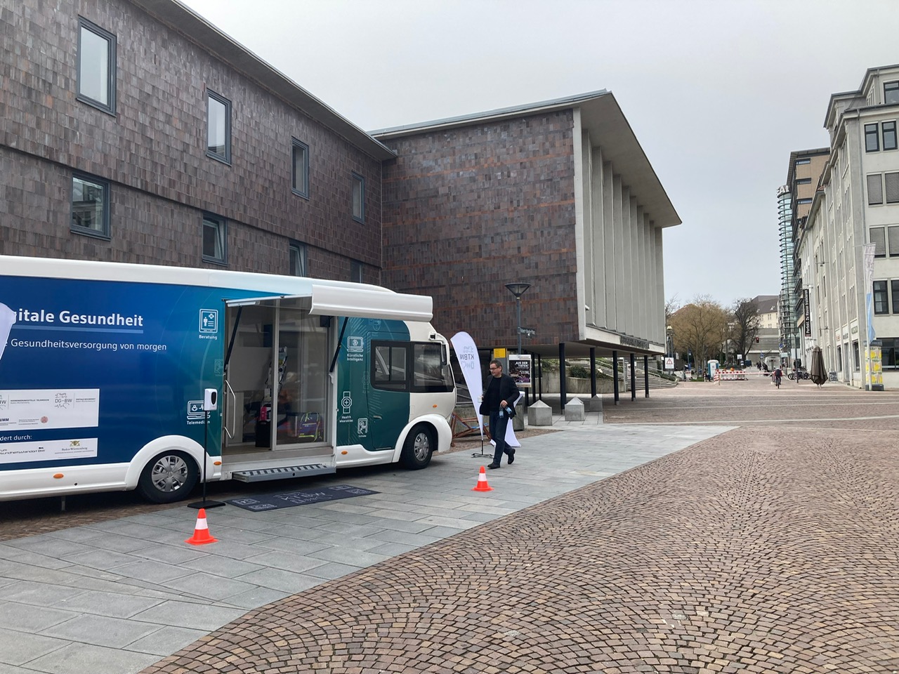 Der Truck steht vor einem großen Gebäude. Ein Mann geht auf den Truck zu.