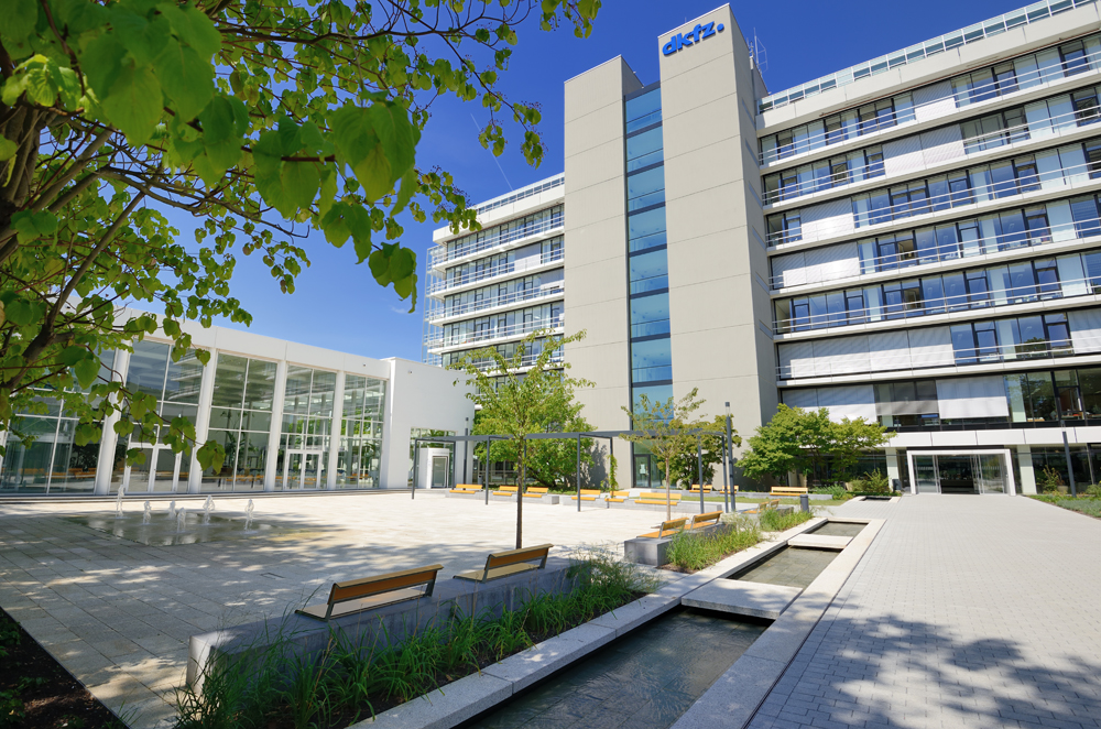 View of the DKFZ high-rise building from a paved square with benches.