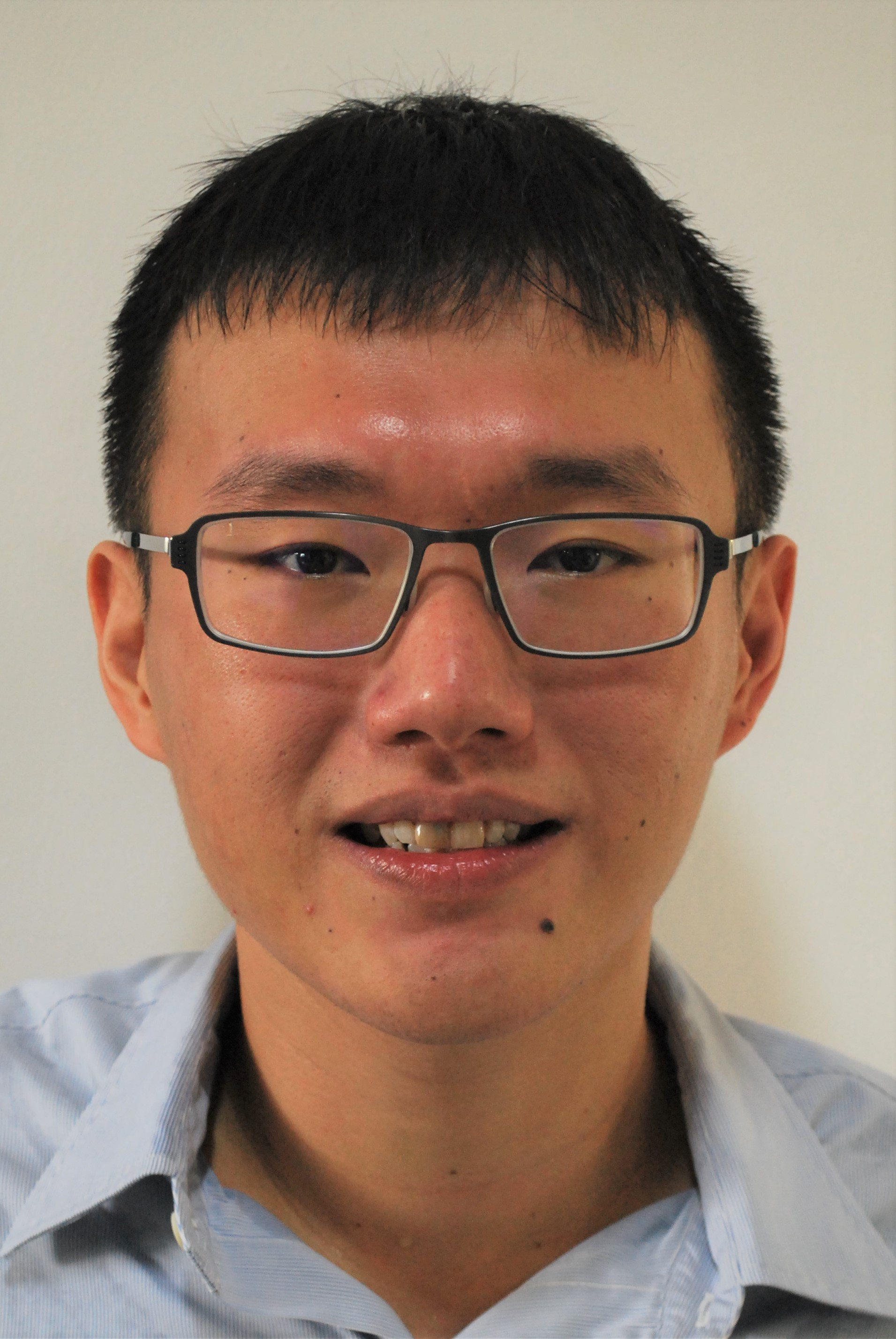 Portrait photo of a young man with short dark hair and dark glasses