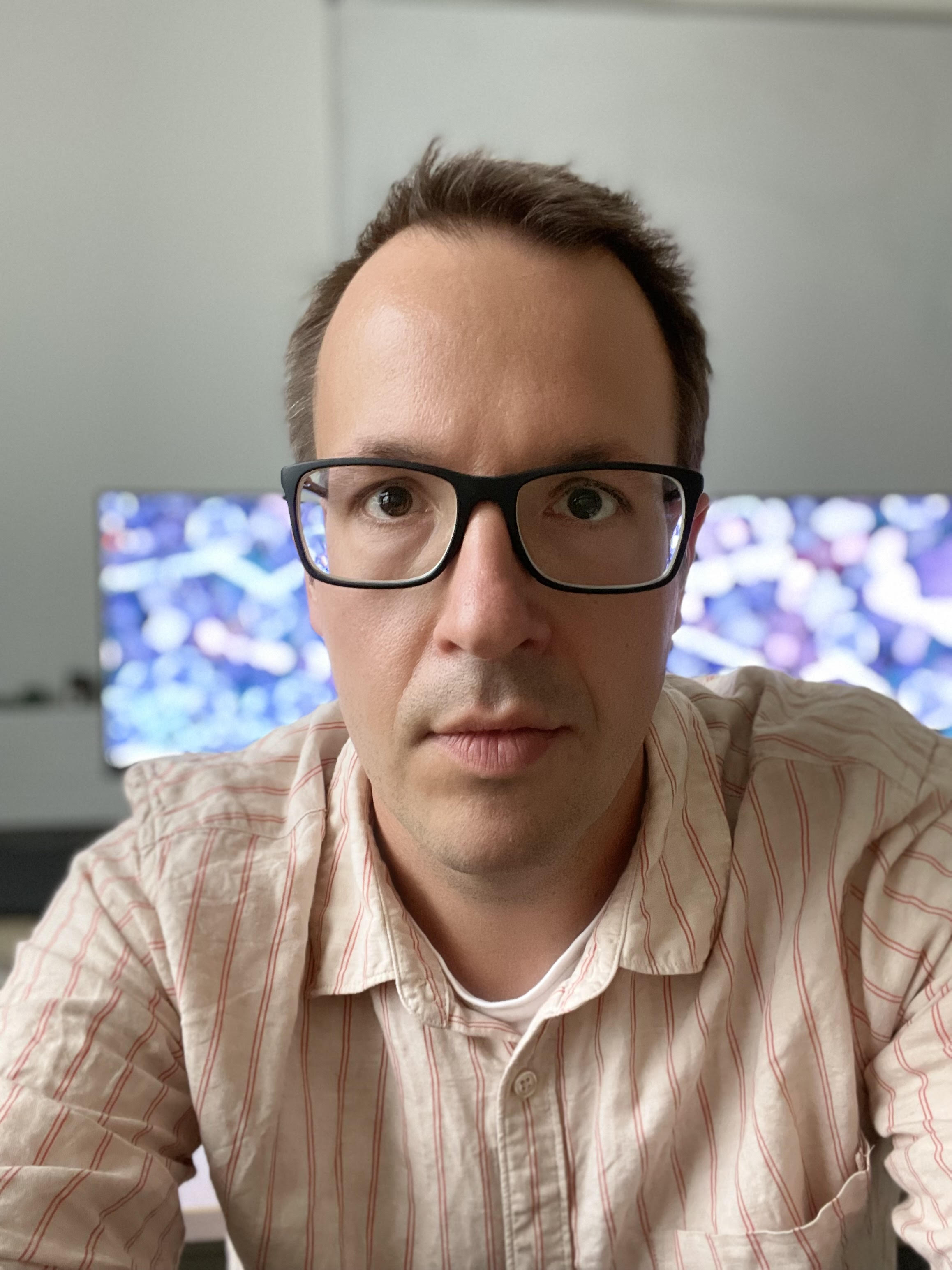 Portrait of a man with short hair and glasses.