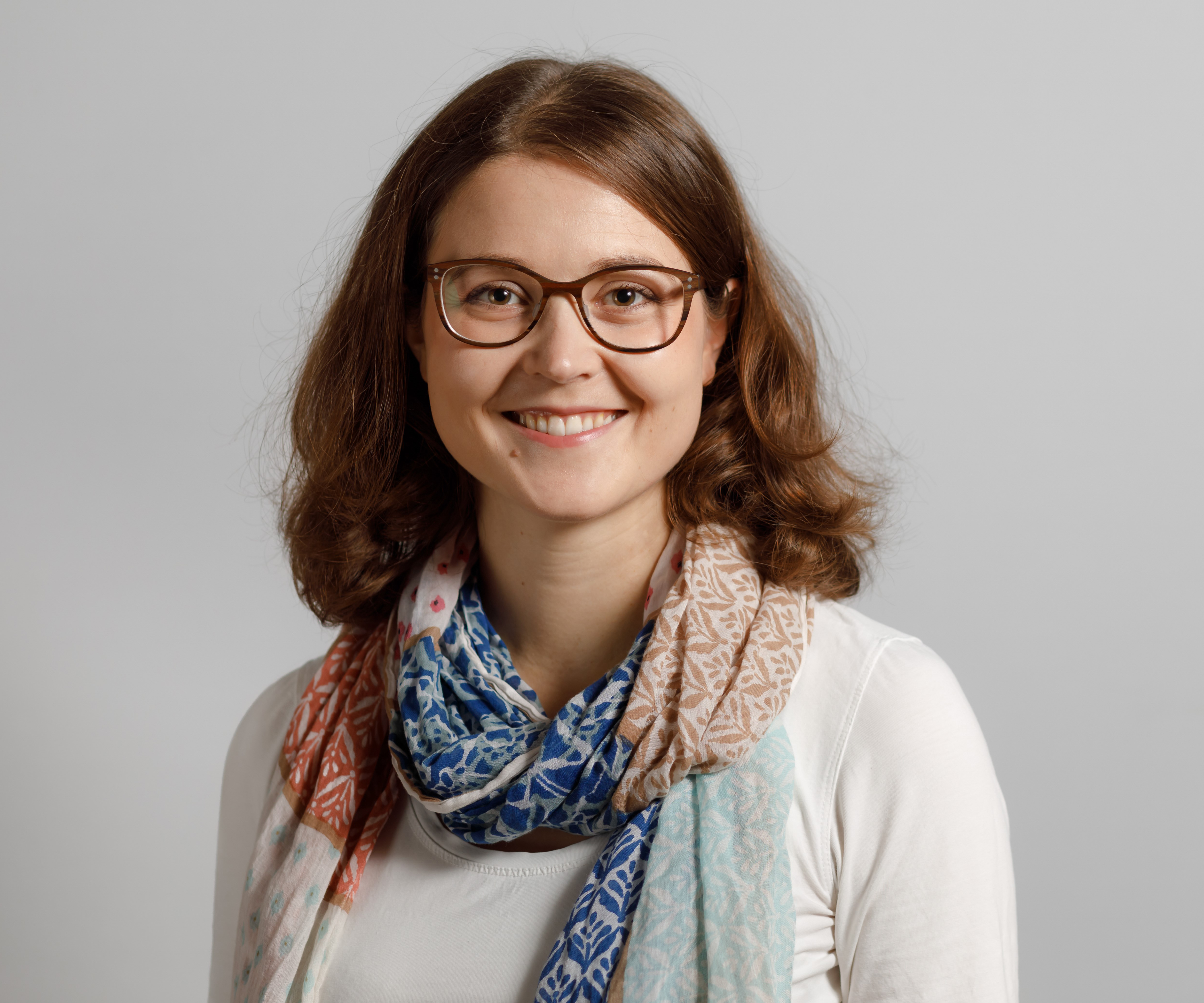 Porträtfoto einer jungen Frau mit mittelblonden, halblangen Haaren und Brille