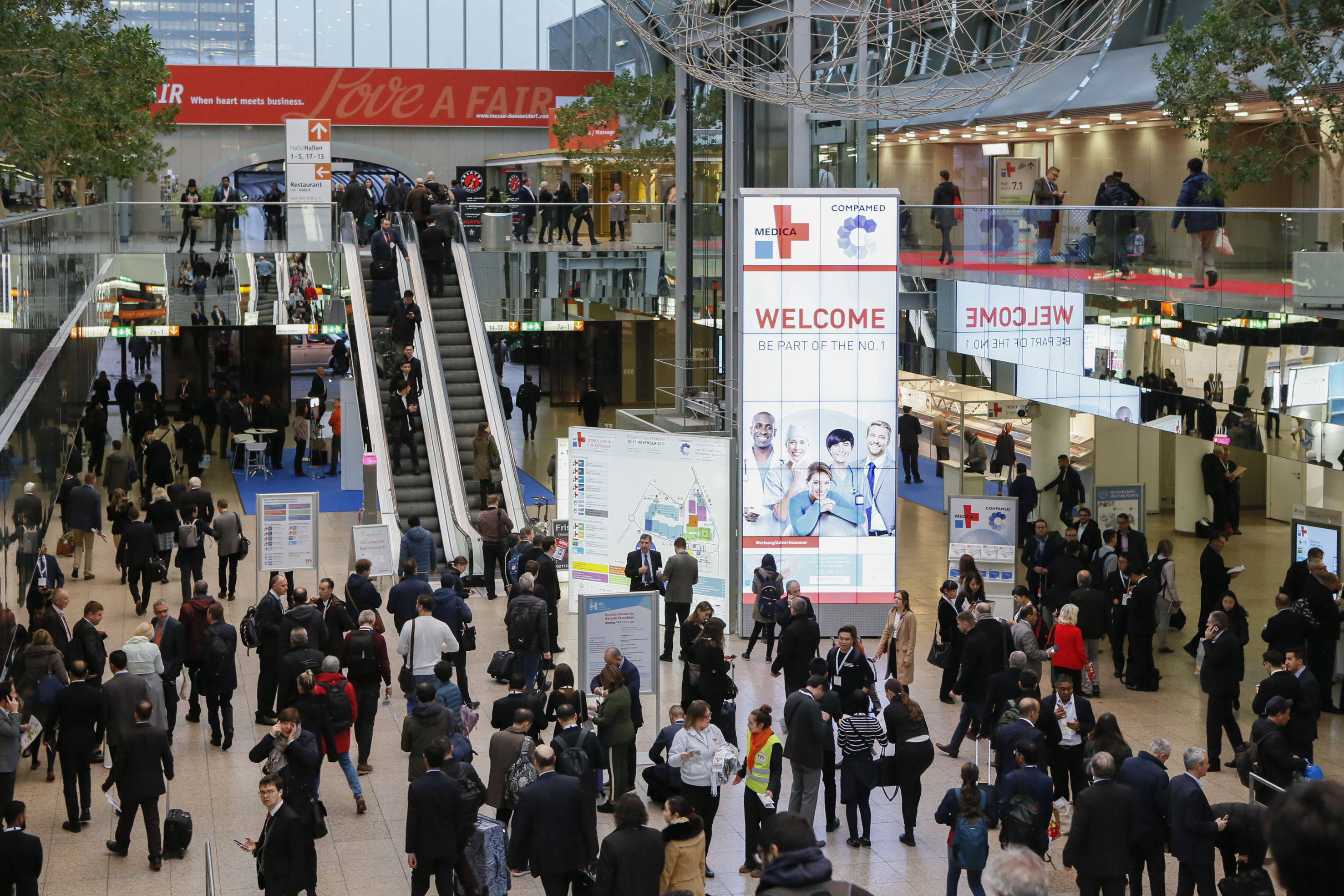 Ankunftshalle in der Messe Düsseldorf, viele Besucher fahren auf einer Rolltreppe.