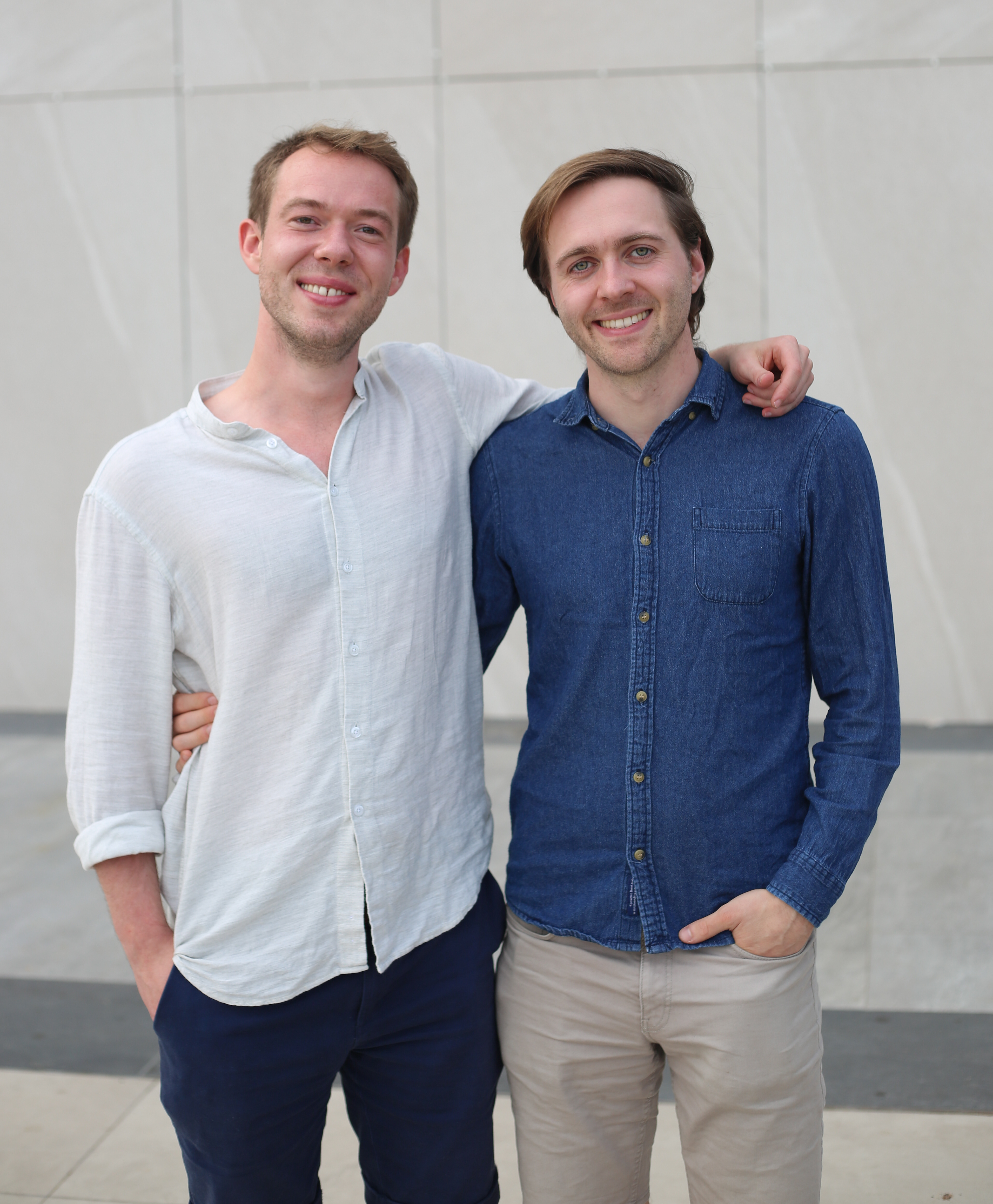 The founders of Actimi GmbH, two young men, stand in front of a building.