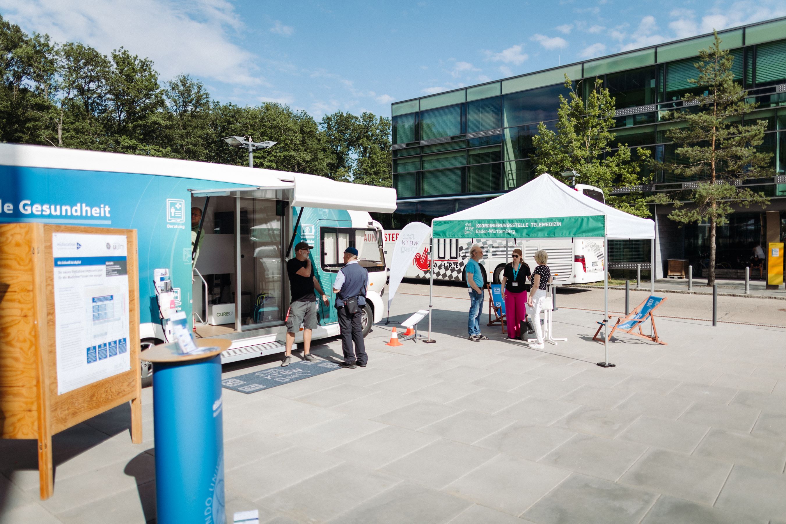 Zwei Männer stehen vor dem Truck. Neben dem Truck steht der Pavillon der KTBW bei welchem es weitere Informationen zu Telemedizin und digitaler Medizin gibt.