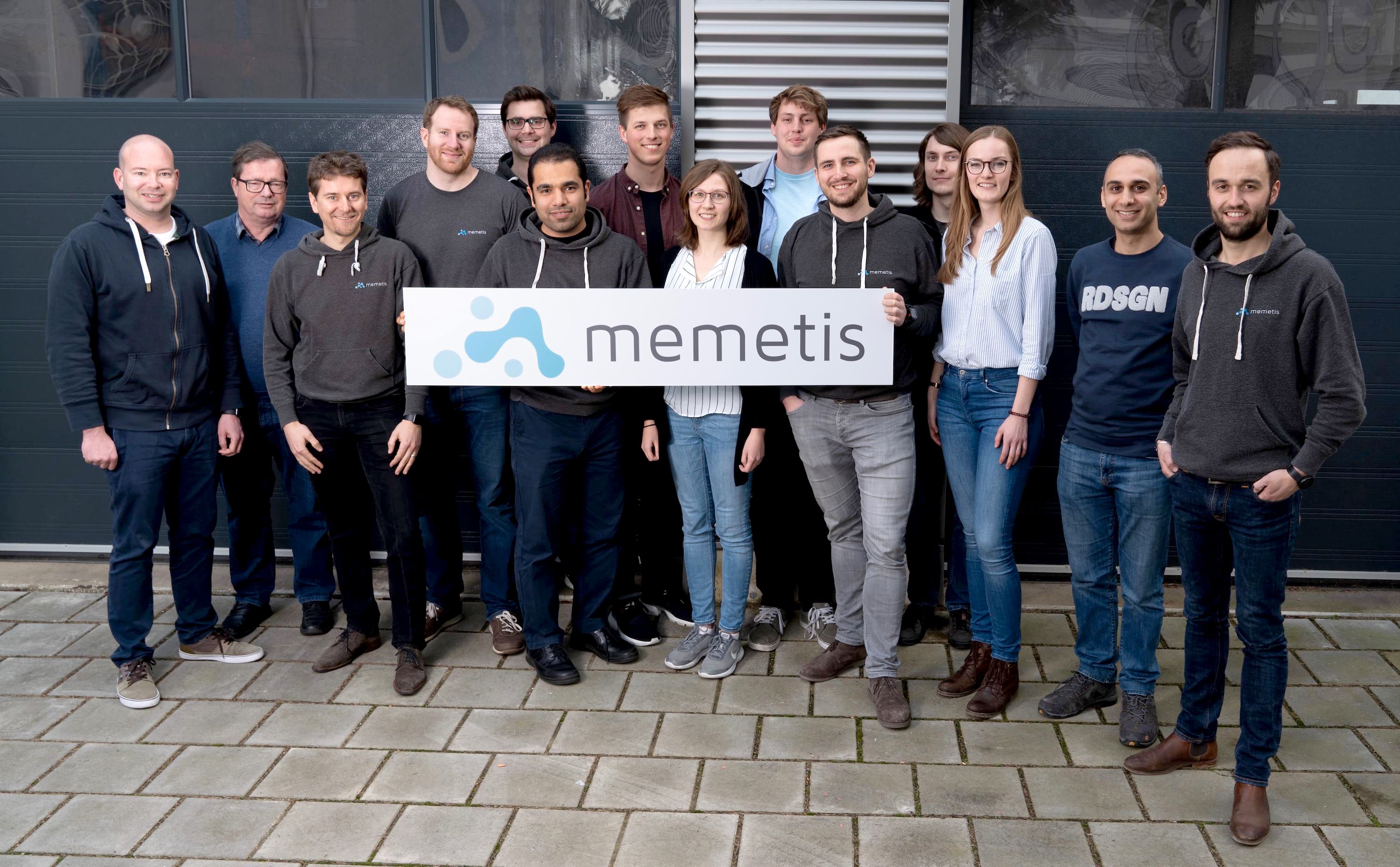 Team of 14 people holding a company sign with the inscription memetis.