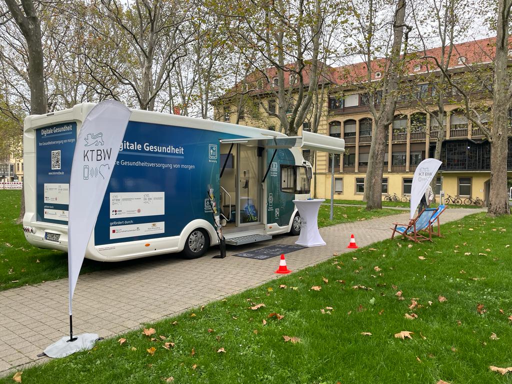 Der Truck steht mit den Liegestühlen und Fahnen vor einem mehrstöckigen gelben Gebäude.