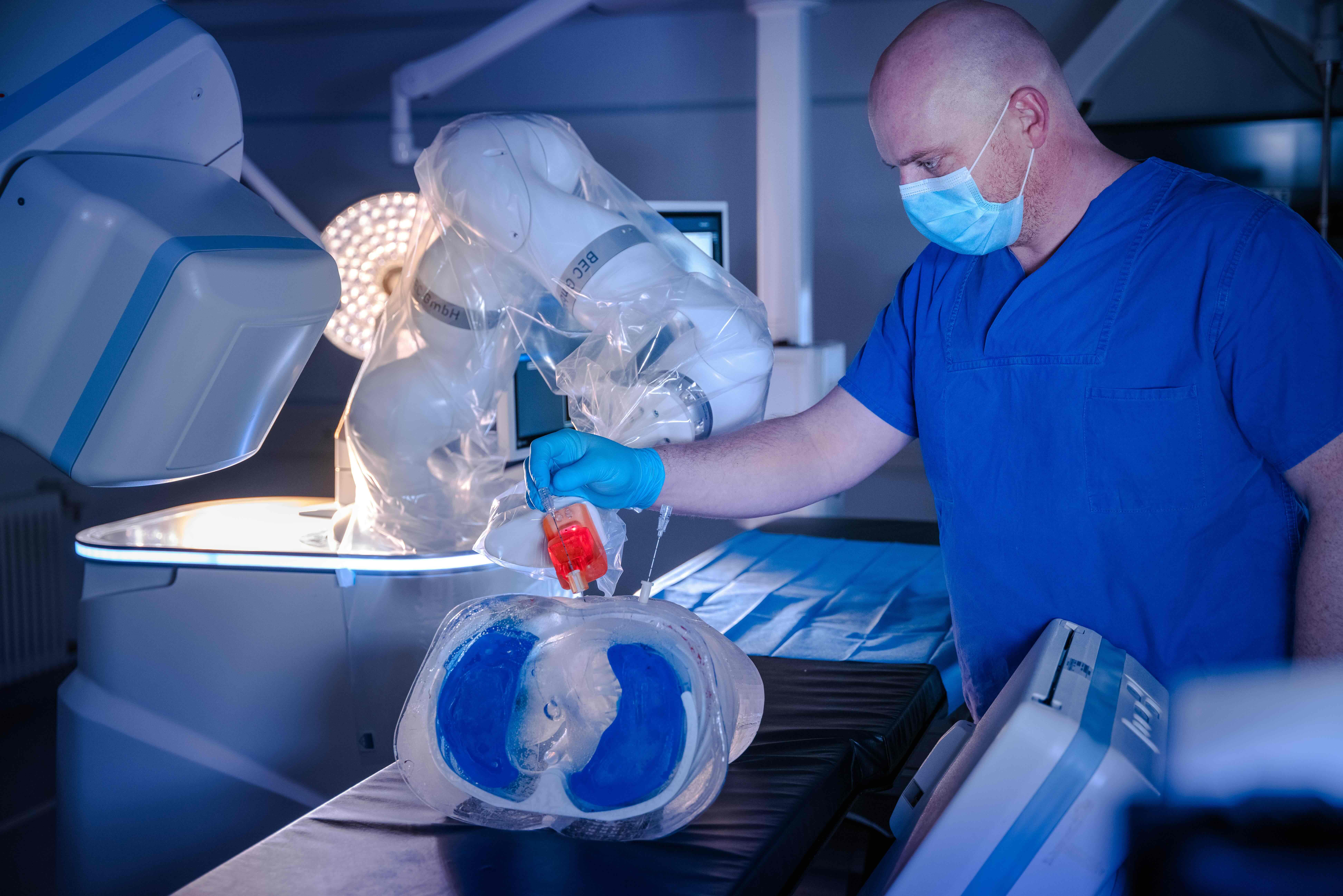 Guidoo’s robotic arm places a guide sleeve on an artificial torso, through which a doctor inserts a biopsy needle.