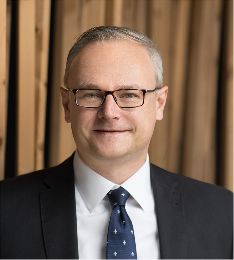 Portrait Martin Ahlhaus: Ein Mann im grauen Jackett mit Krawatte und Brille