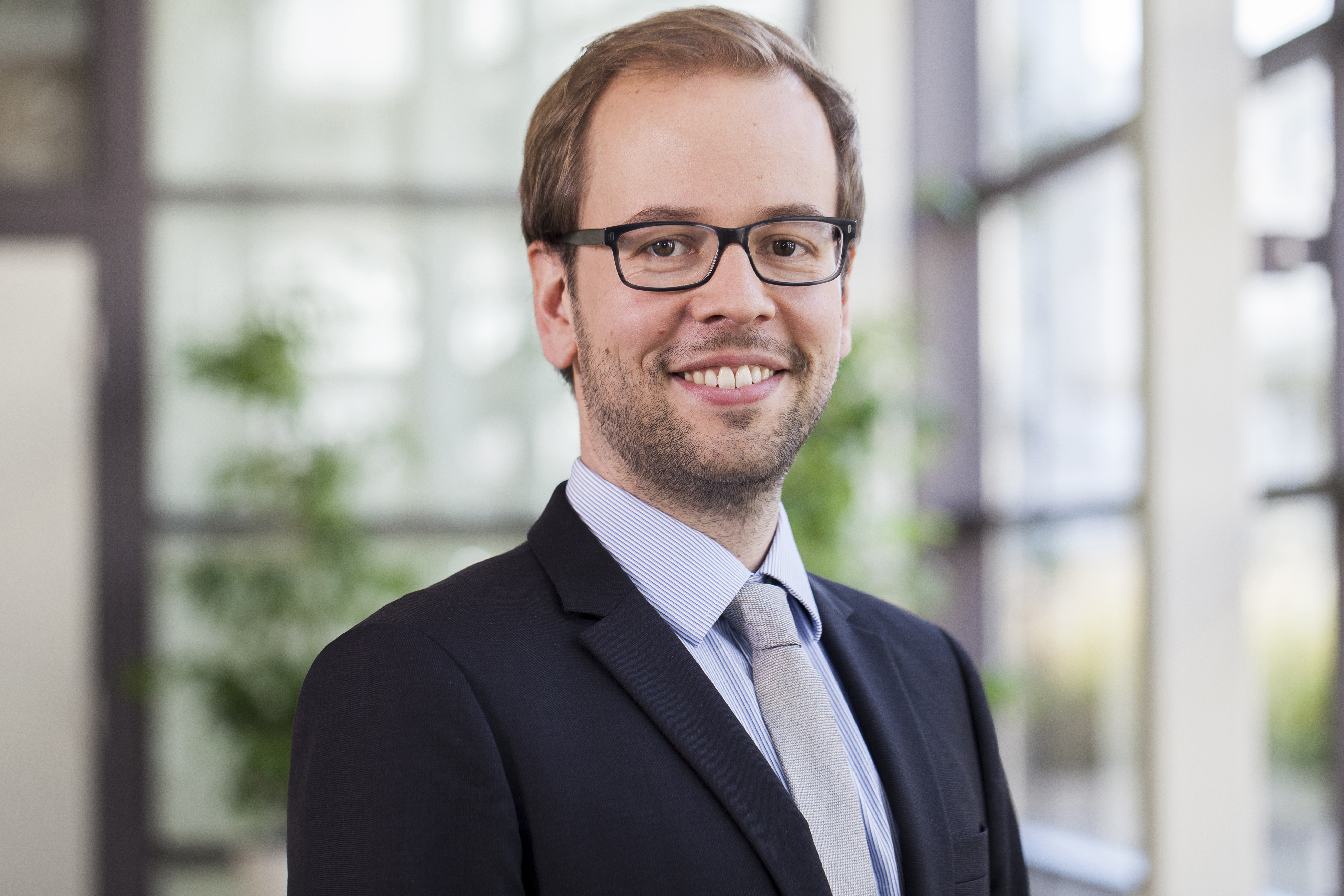 Portrait of a blond man in a suit with glasses.