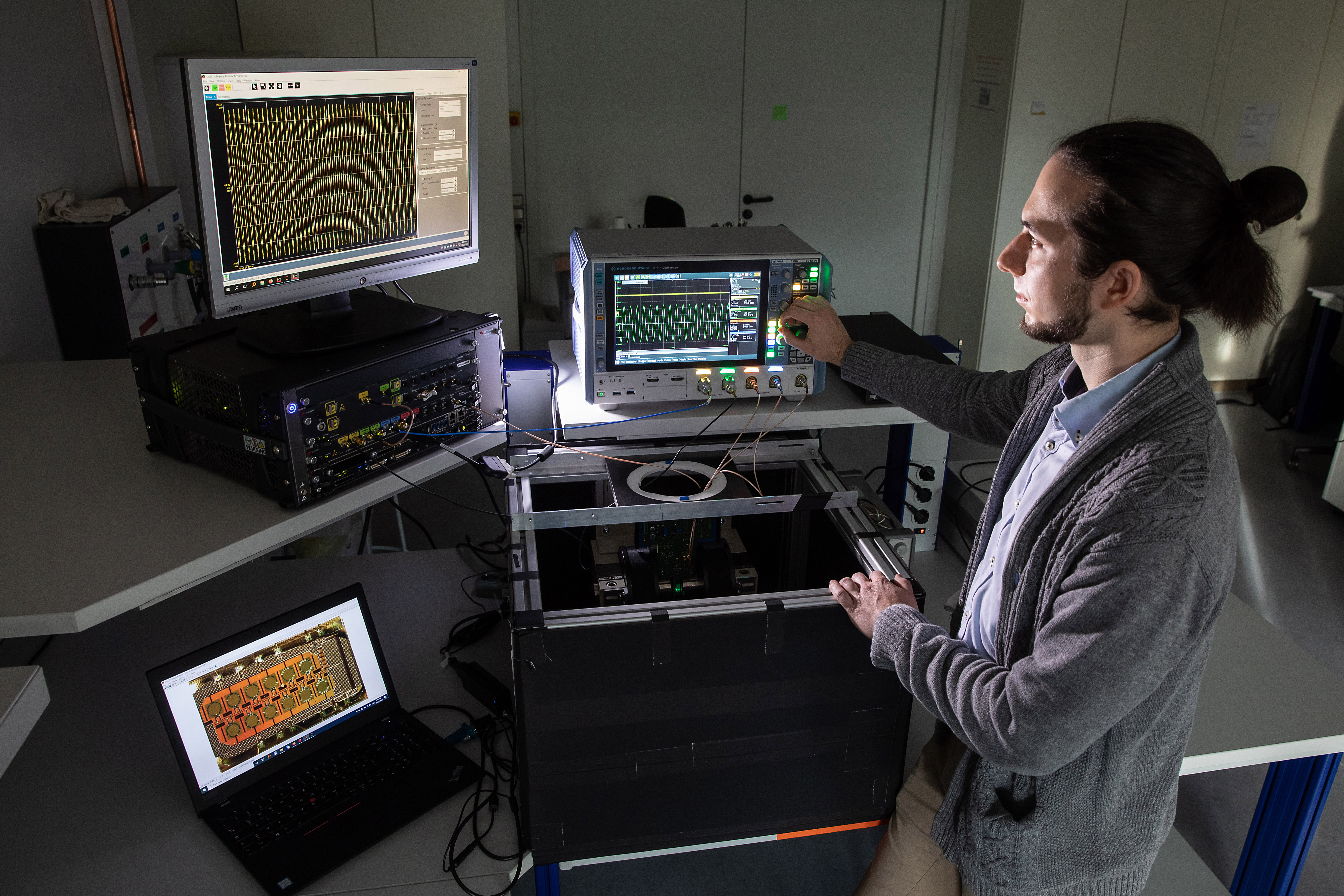 Person in the lab in front of various computer screens.