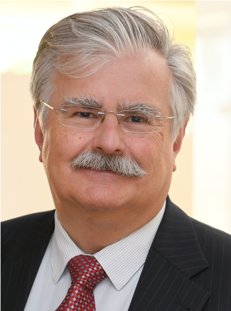 Portrait photo of an older man with glasses and grey hair in a suit.