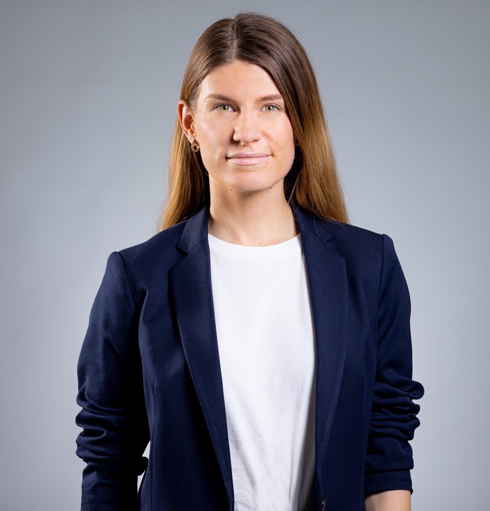 Photo of a woman with long brown hair in a dark blazer.