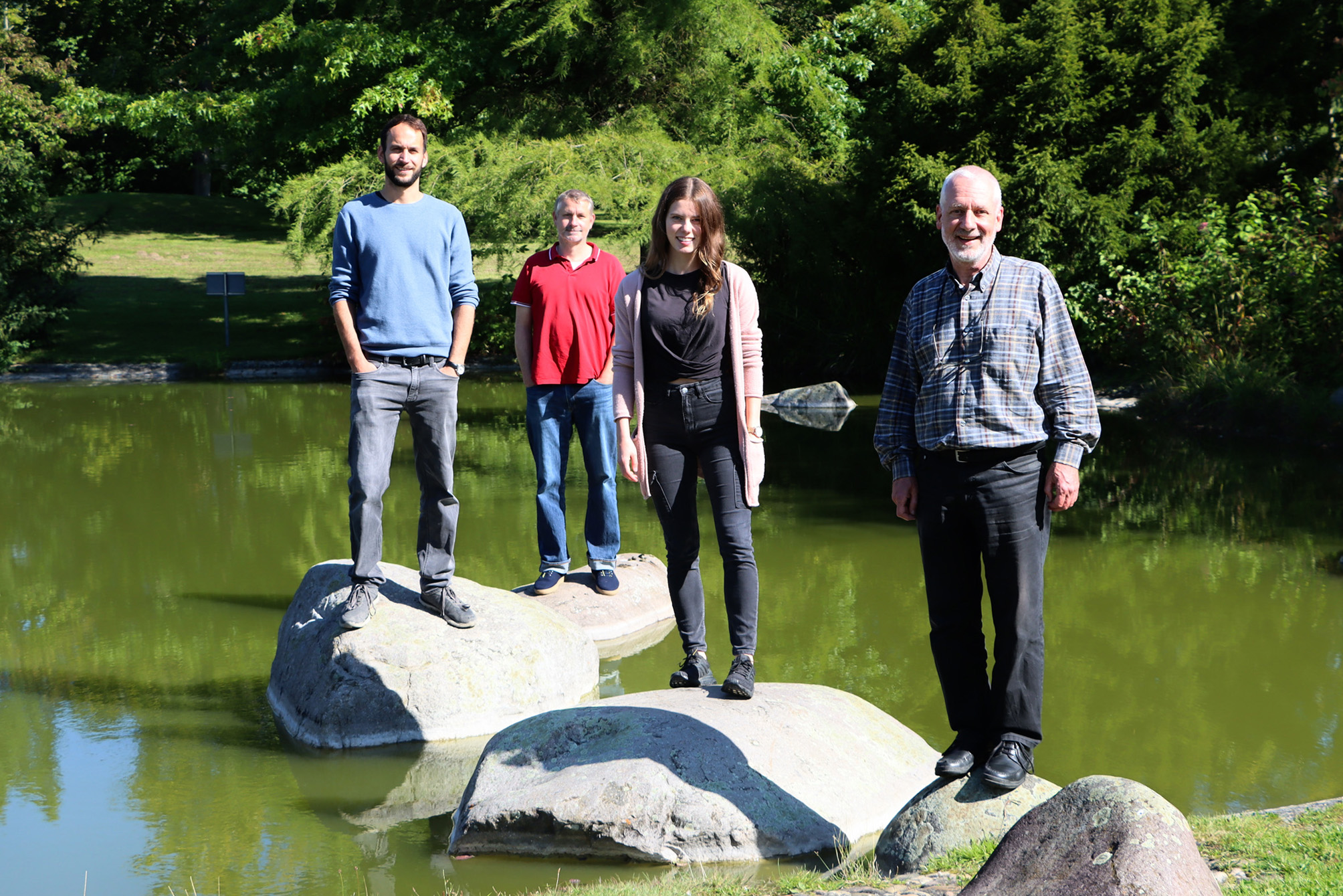 The team stands on large stones in a pond.