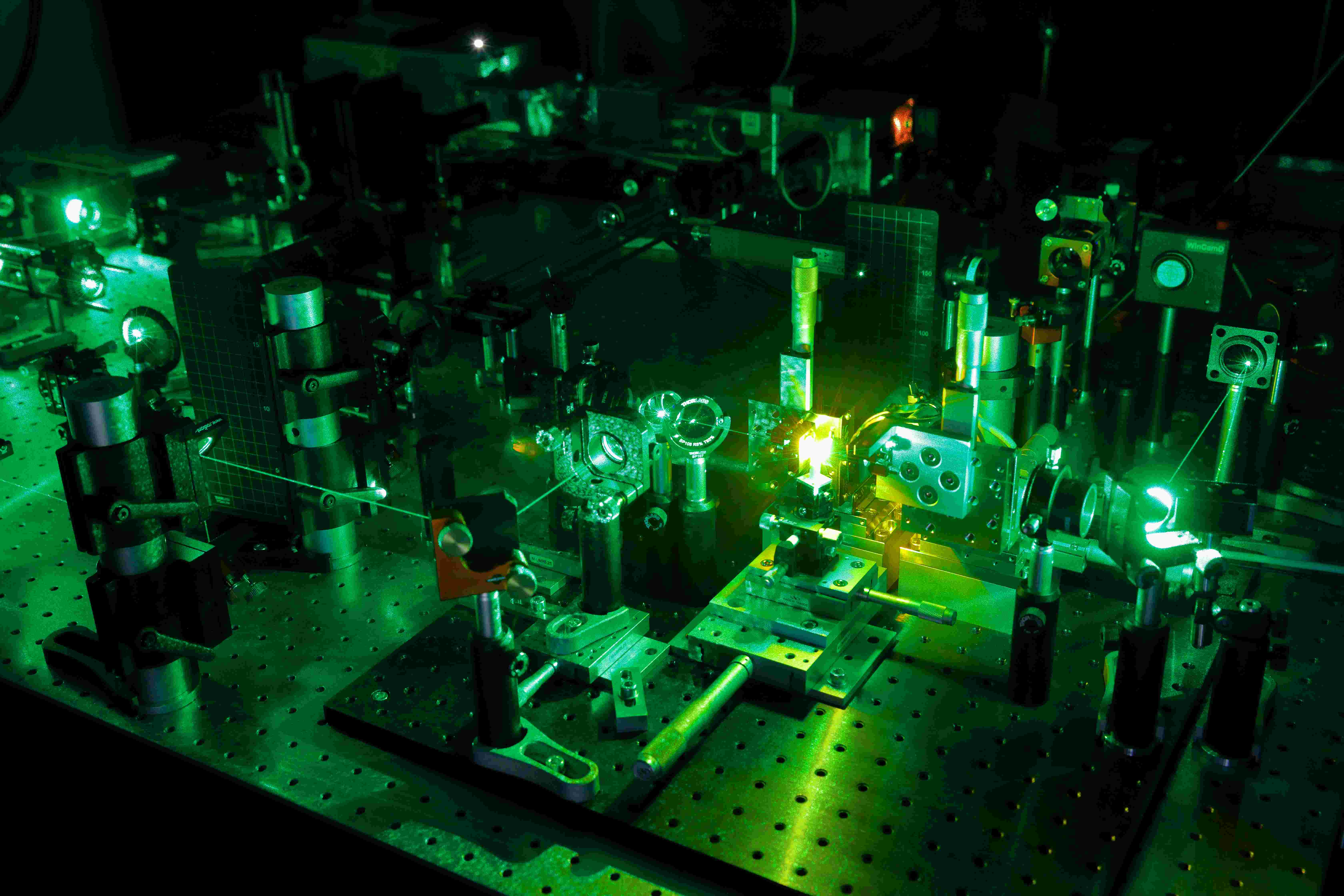 Laboraufbau, in dem ein grüner Laserstrahl durch verschiedene Instrumente fällt.