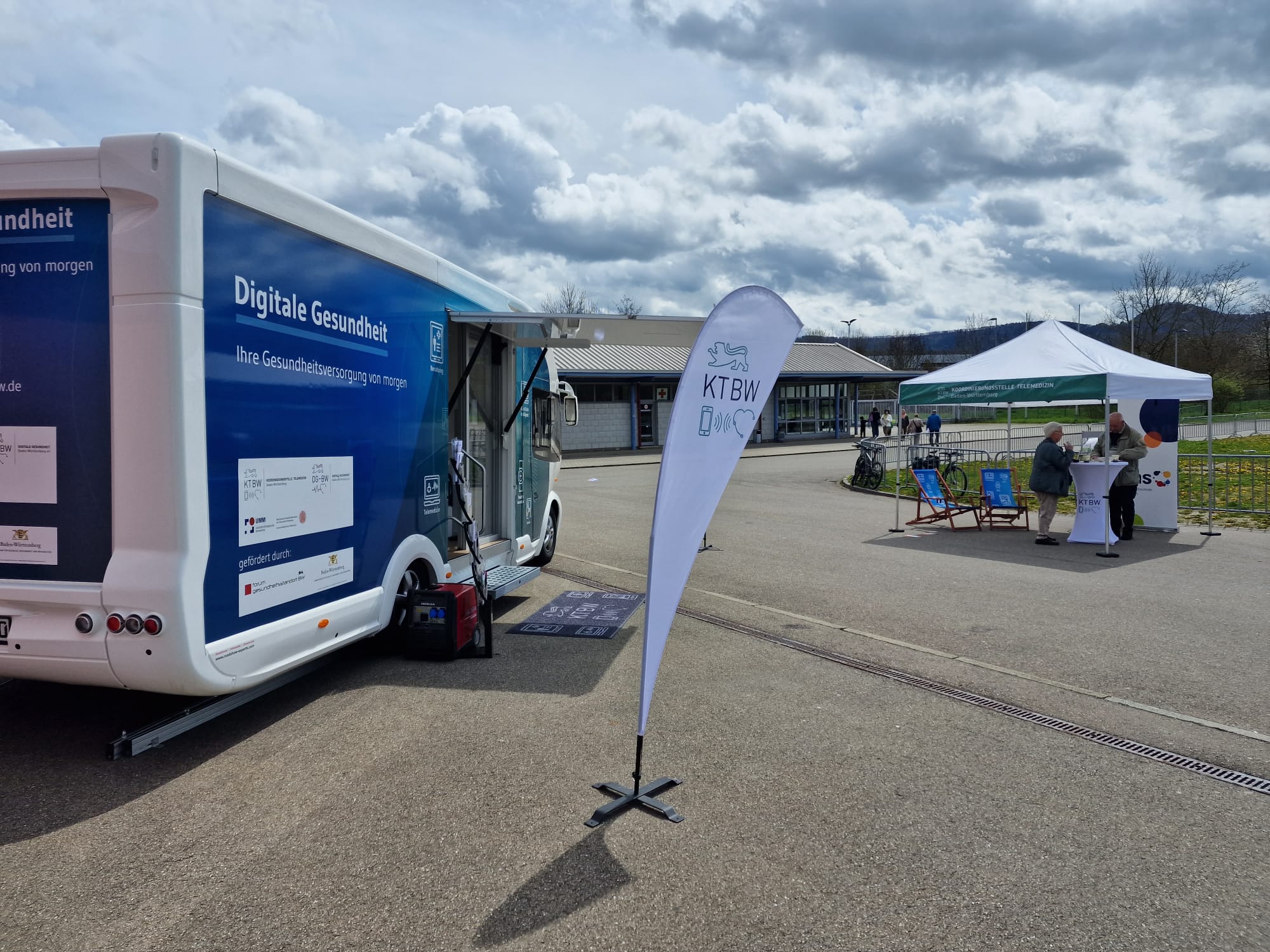 Der Truck steht auf einer asphaltierten Fläche. Neben dem Truck ist der Pavillon der Koordinierungsstelle Telemedizin zu sehen.