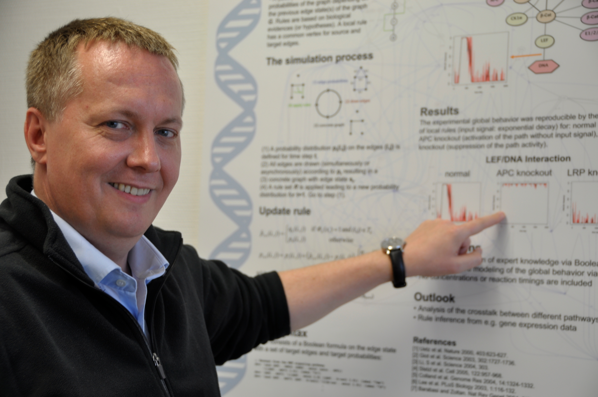 Der Ulmer Bioinformatiker Hans Kestler zeigt mit dem Finger auf ein wissenschaftliches Poster.