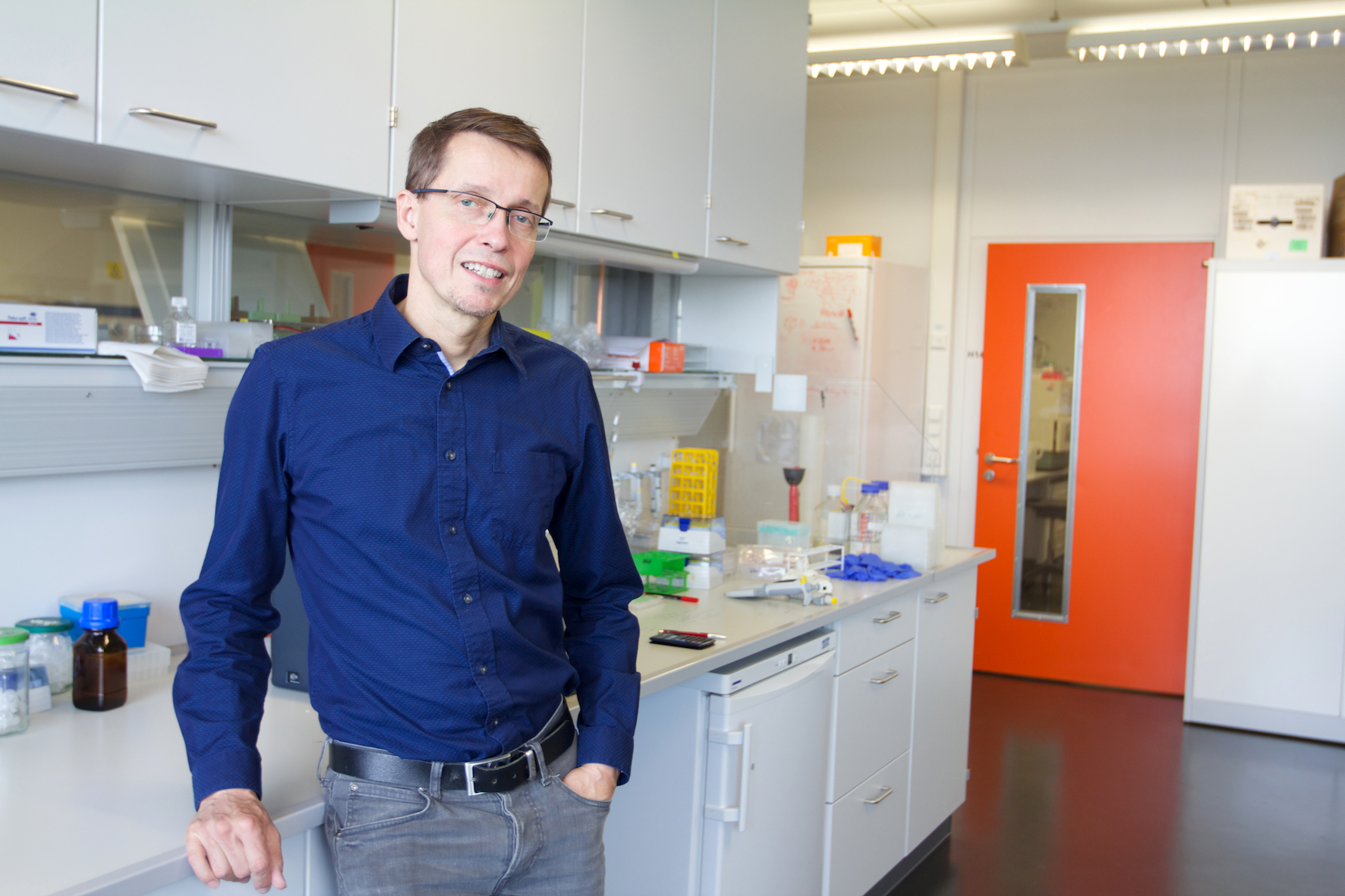 The photo shows Prof. Dr. Andreas Peschel standing in front of a laboratory bench