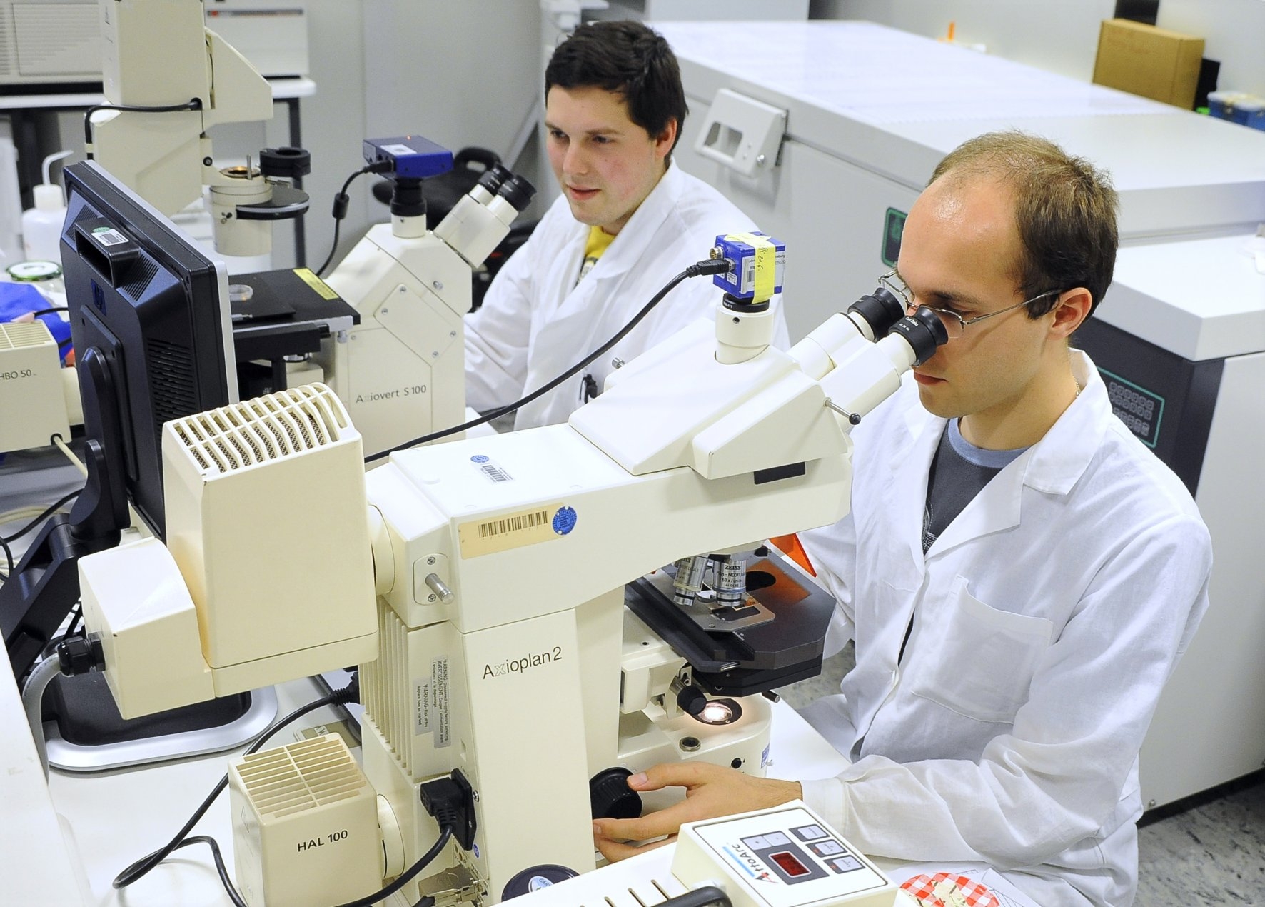 Zu sehen sind zwei Wissenschaftler beim Mikroskopieren.