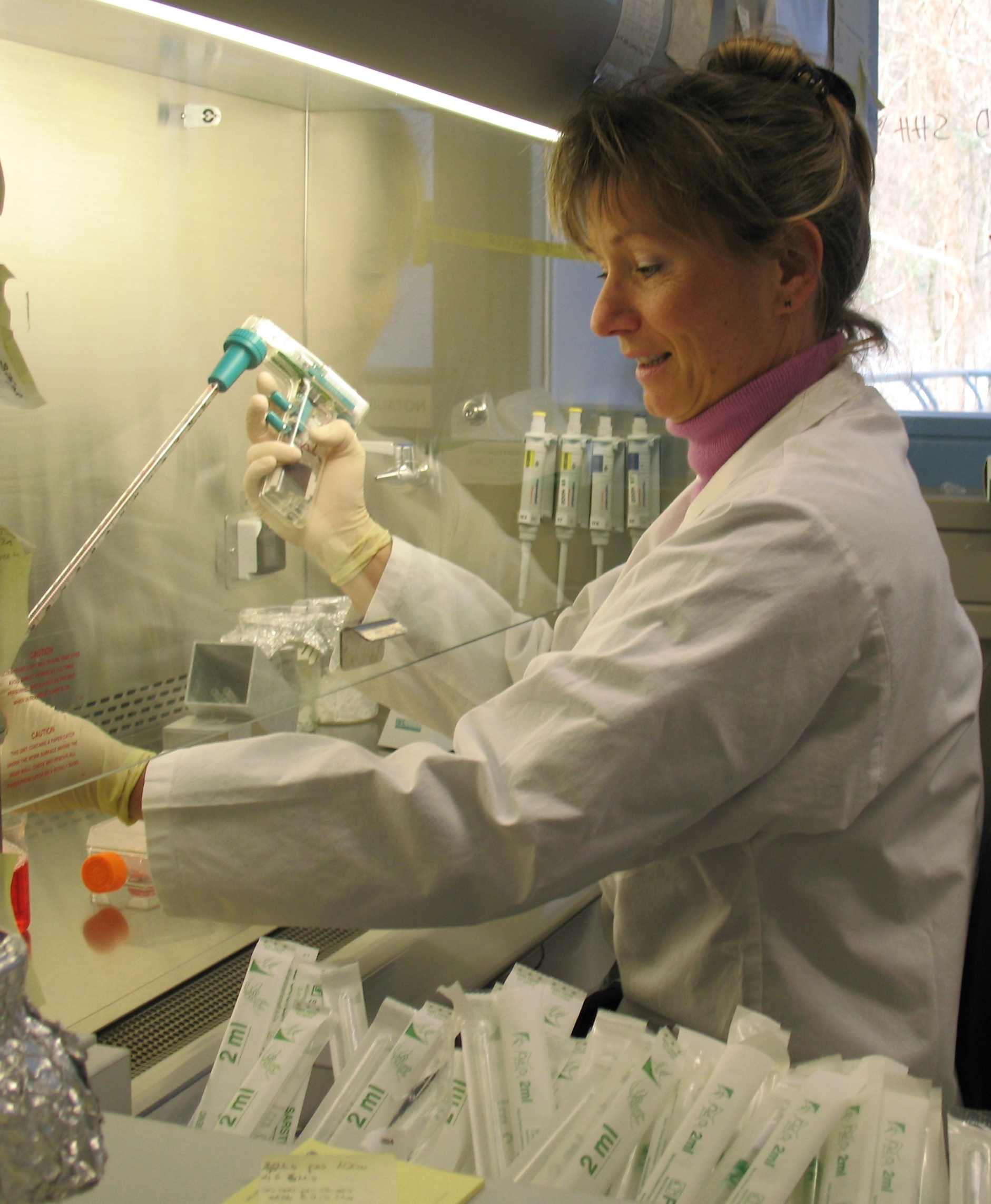 The photo shows Dr. Suzanne Kadereit working at a laminar flow cabinet in the university's cell culture laboratory.