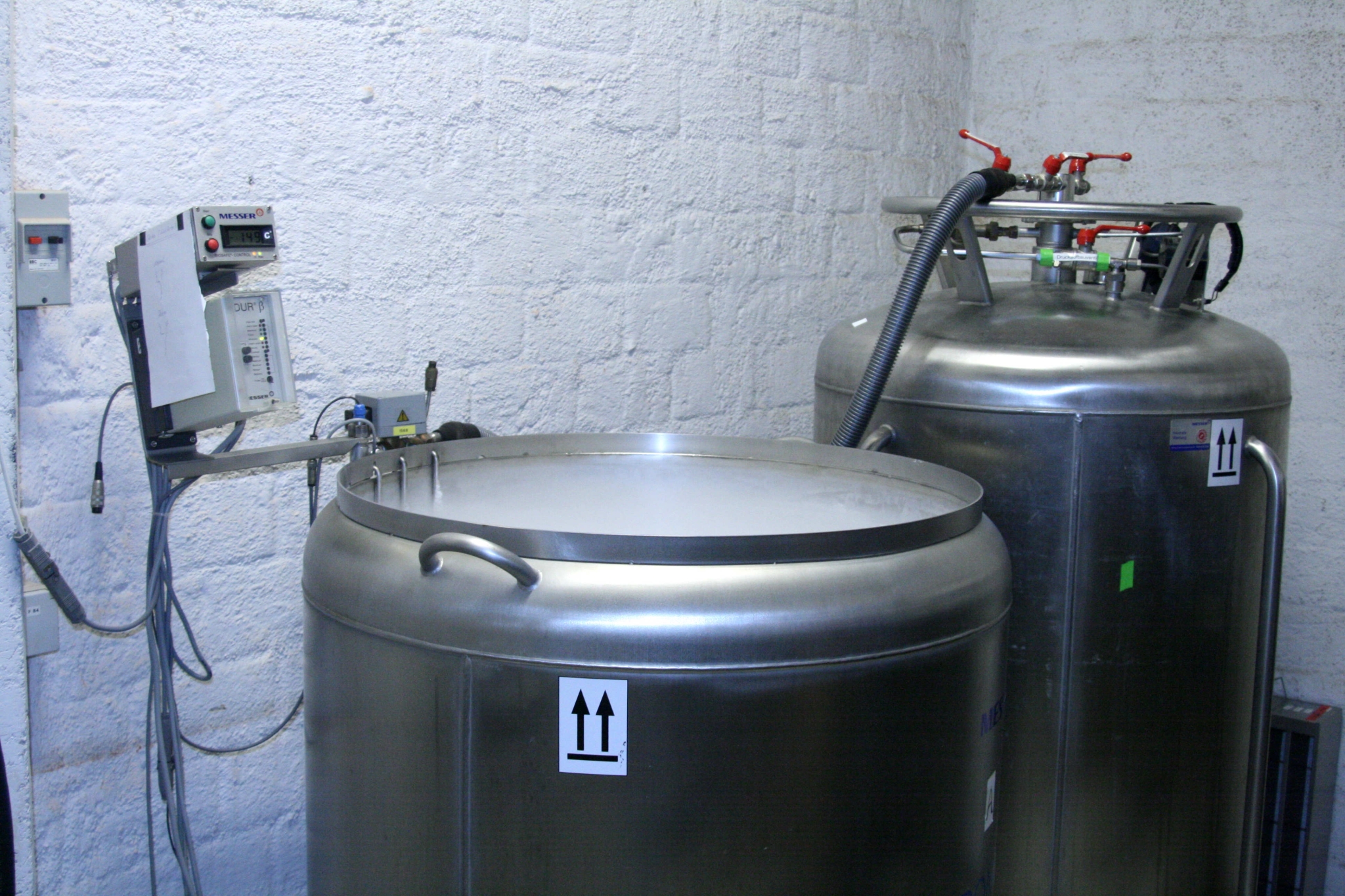 The photo shows a metal container from which white steam extrudes. The container is connected to another metal container via a tube, and to a small electronic box via cables.