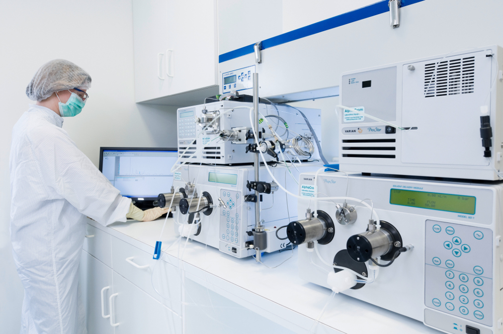 An HPLC system used for the purification of RNA can be seen on the right-hand side. On the left-hand side, a CureVac employee in a white coat can be seen to operate the system.
