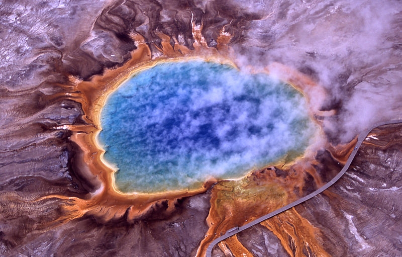 Ein Vulkankrater im Yellowstone National Park: Der See in der Mitte ist von einem orange leuchtenden Ring aus Algen und Bakterien umgeben, die sich an die extrem heiße Umgebung physiologisch angepasst haben.