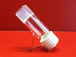 Small glass vial filled with whitish hydrogel and turned upside down. The hydrogel's consistency makes it adhere to the glass and prevents it from flowing out of the vial.