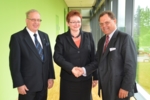 Zu sehen sind drei Personen: Prof. Dr. Günter Rexer (l.) und Udo J. Vetter (r.) gratulieren Dr. Ingeborg Mühldorfer.
