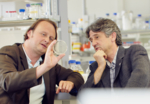 Zu sehen sind Andreas Marx und Martin Scheffner im Labor bei der Betrachtung einer Petrischale.