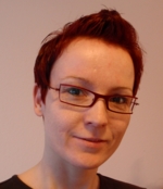 Dr. Janine Reis. Zu sehen ist das lächelnde Gesicht einer Frau mit kurzen roten Haaren und Brille.