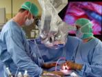 Photo showing an urology operating theatre during urinary bladder operation. The photo shows two members of the operation team standing on the left- and right-hand side of the patient.