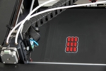 The photo shows a lateral view of a typical printer with a red blister pack to symbolise the suitability of printers for the production of drugs.