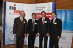 The photo shows four men standing in front of a modular display system.