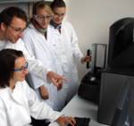 Vier Studierende (hier: Master-Studenten) im Labor mit Schutzbrillen.