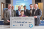 Seven people holding a check indicating the donated sum of 20.000.000 euros.