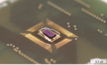 Farbige Nahaufnahme des Silizium-Chips (lila), der über feine Golddrähte mit der Trägerplatine verbunden ist.