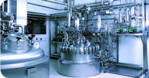 Zu sehen ist ein Teil einer biotechnologischen Produktionsanlage. Ein großer Bioreaktor für die Anzucht von Säugetierzellen ist das zentrale Element des Bildes.