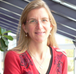 Das Bild zeigt ein Protrait von Julia Kirchheiner. Sie hat blonde lange Haare, trägt eine Brille und einen roten Pullover.