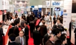 Zu sehen ist ein Gang auf der Ausstellung der MEDTEC Japan 2013. Es sind viele Messebesucher dort, die sich an Aussteller-Ständen aufhalten.