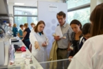 Eine Schülerin erläutert einem anwesenden Lehrer die Gelelektrophorese.