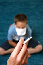 Das Bild zeigt einen rauchenden Erwachsenen, im Hintergrund ein Kind mit verbundenem Mund.