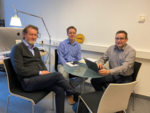 Zu sehen sind Prof. Dr. Oliver G. Opitz, Florian Burg und Dr. Armin Scherer sitzend um einen Tisch herum.