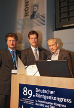 Professor Doktor Michael Laniado und Professor Doktor Dierk Vorwerk überreichen den Wilhelm-Conrad-Röntgen-Preis an Professor Doktor Martin Bendszus.