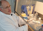 Prof. Dr. Wilhelm K. Aicher mit weißem Laborkittel sitzt an einer Sterilbank und pipettiert.