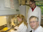 The photo shows Hanne Gerding, Dr. Christiaan Karreman and Dr. Stefan Schildknecht in the laboratory standing close to/sitting at a clean bench.