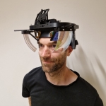 A man in black t-shirt with a model of AR glasses on his head.