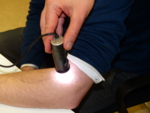 Ein Dermatoskop wird ähnlich einer kleinen Lampe auf den Unterarm eines Patienten gehalten.